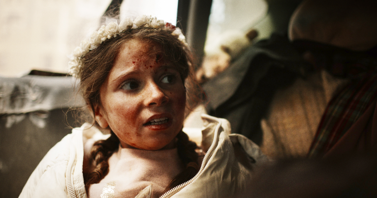 Meisje van vijf met bloed op haar gezicht zit op de achterbank van een auto