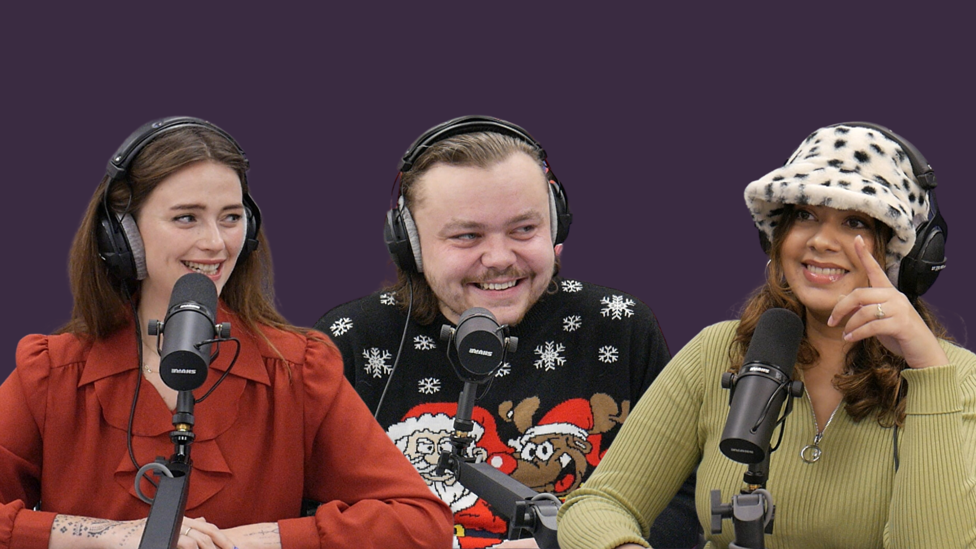 Foto met drie lachende personen. Allemaal dragen ze een zwarte koptelefoon en zitten ze voor podcastmicrofoons. De linker vrouw draagt een rode blouse. De man bovenaan draagt een kersttrui met de kerstman, een rendier en sneeuwvlokken. De rechter vrouw draagt een witte hoed met zwarte stippen en een groen shirt met lange mouwen.