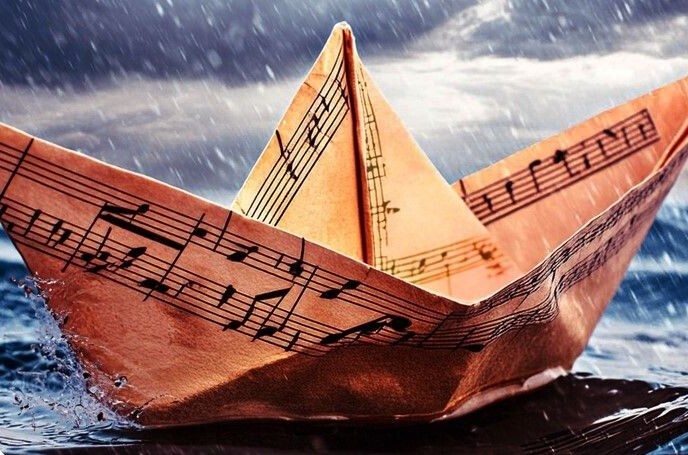 Een papieren bootje van een muziekblad die drijft in zee in de stromende regen.