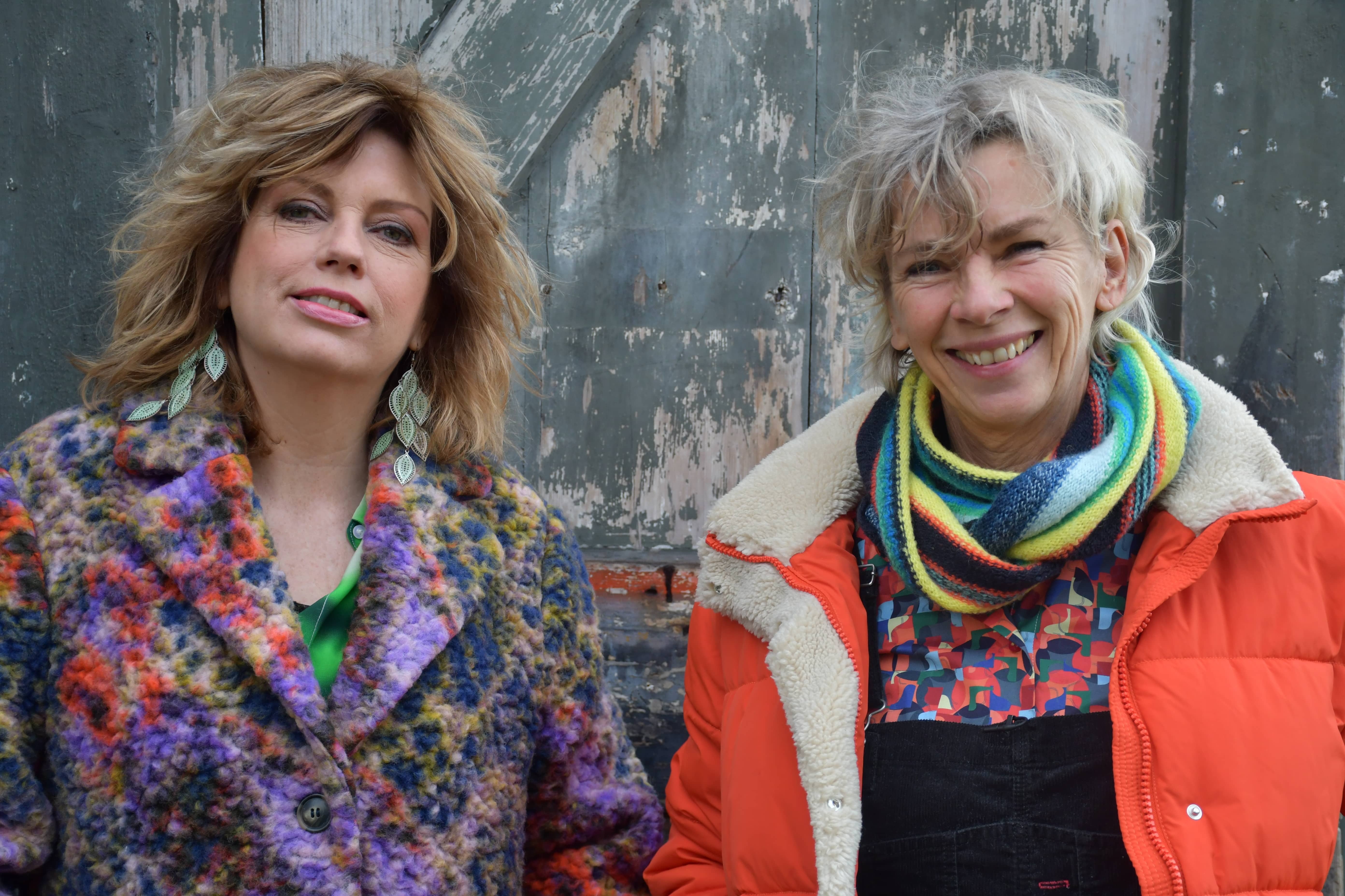 Twee vrouwen staan lachend naar de camera