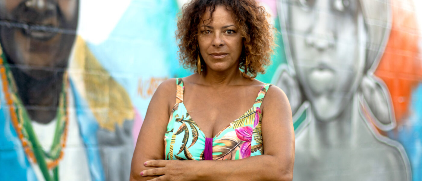 Nina Jurna staat voor een muurschildering met een vrolijke top aan