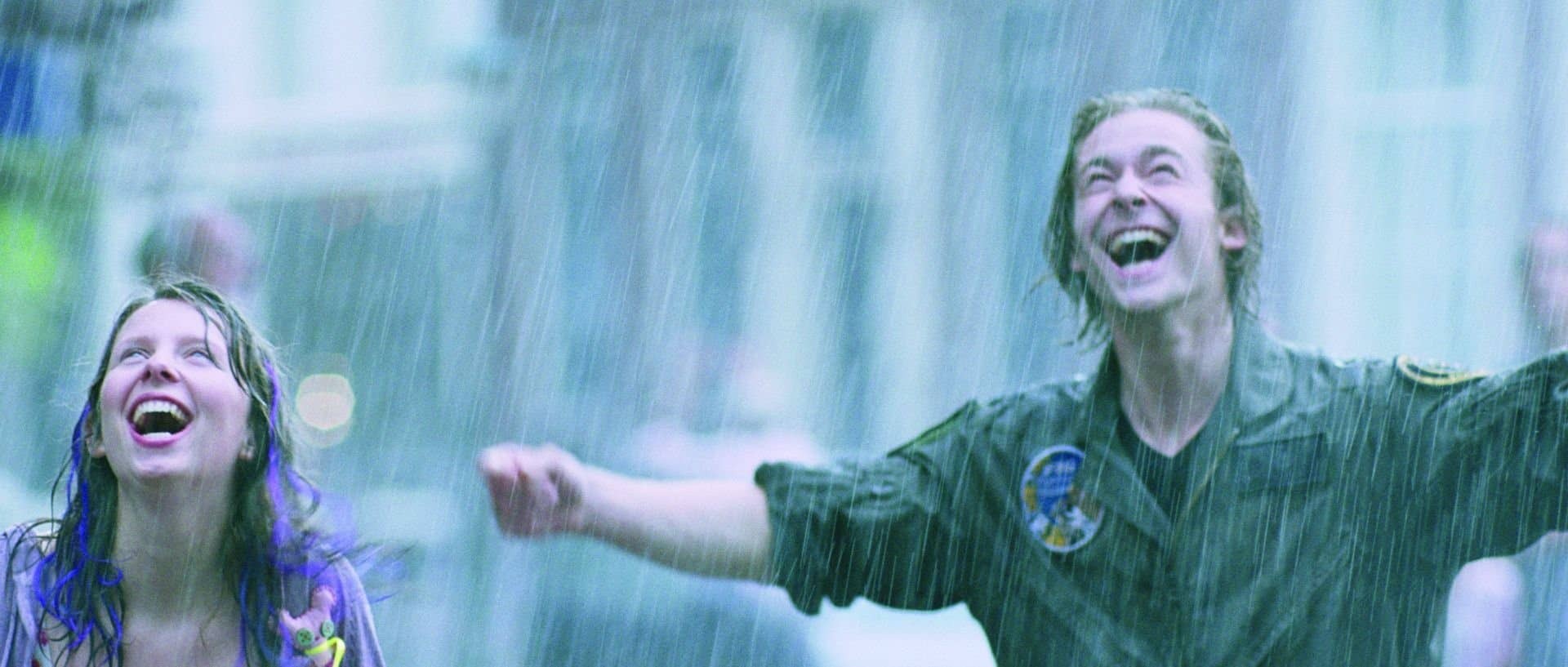 Twee mensen staan dolgelukkig in de regen