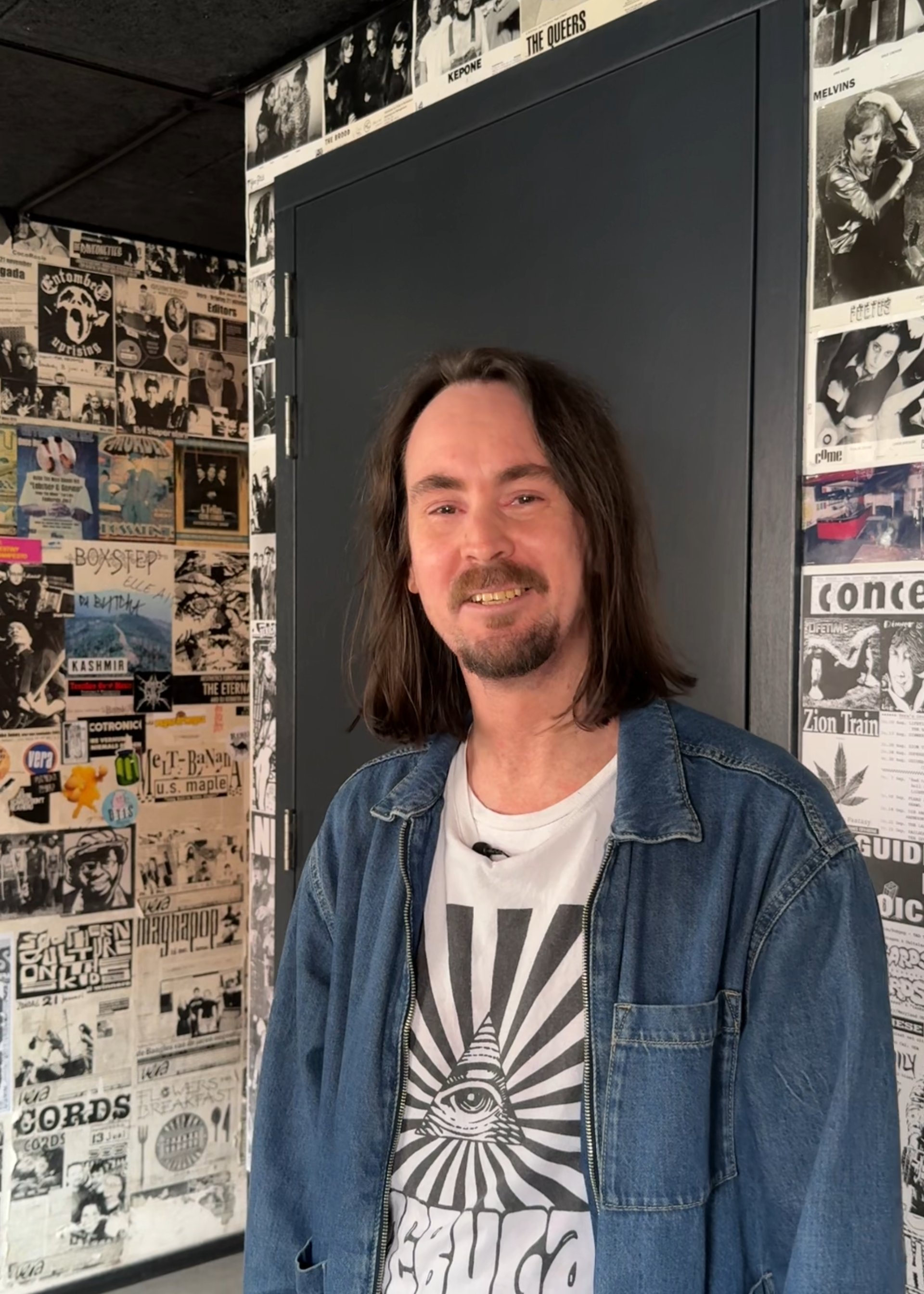 Portretfoto van artiestenbegeleider Mark. Mark kijkt vriendelijk de camera in en staat in een hal.