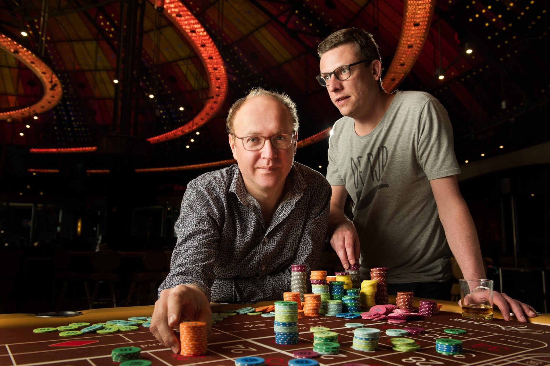 Twee mannen zit rond een tafel vol pokertokens