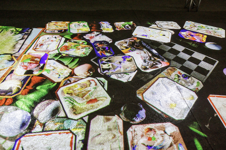 Kunstwerk met geprojecteerde spellen op de vloer.