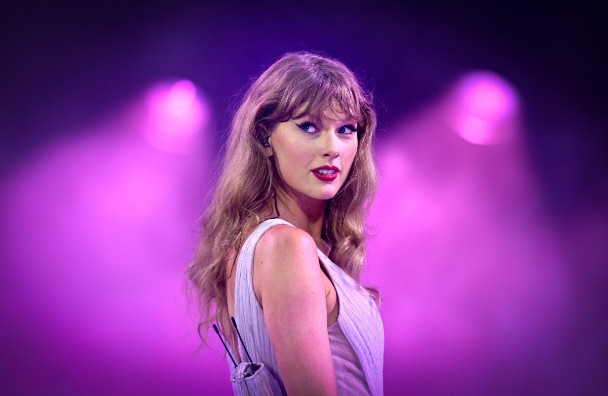 Blonde Amerikaanse zangeres Taylor Swift kijkt zwoel naar de camera met een roze achtergrond.