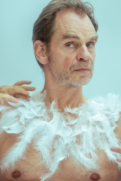 Hier is een man te zien met een ontbloot bovenlichaam met veren er op geplakt.