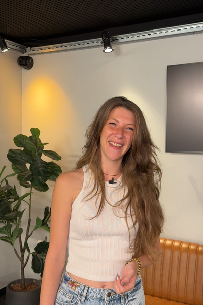 Foto van Nikki, waar dit artikel over gaat. Ze kijkt lachend de camera in. Zee heeft lang haar wat ze los draagt.