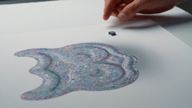 Fotoprint van de grijze XTC-pil in de vorm van een uil naast de echte pil.