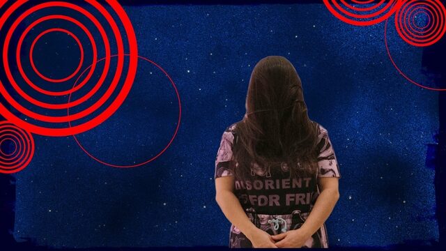 Susanne khalil yusef staat tegen een blauwe achtergrond, met haar handen op haar rug.