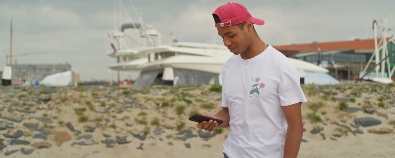 Jonge jongen met mobiel op het strand