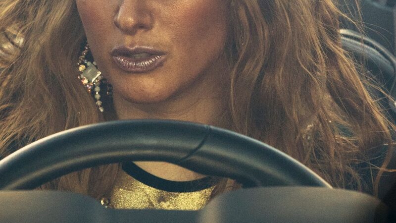 Een prachtige vrouw met gouden make-up zit achter het stuur