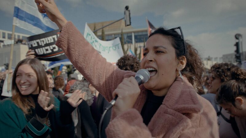 Noam Shuster-Eliassi staat in een demonstratie en roept in een microfoon