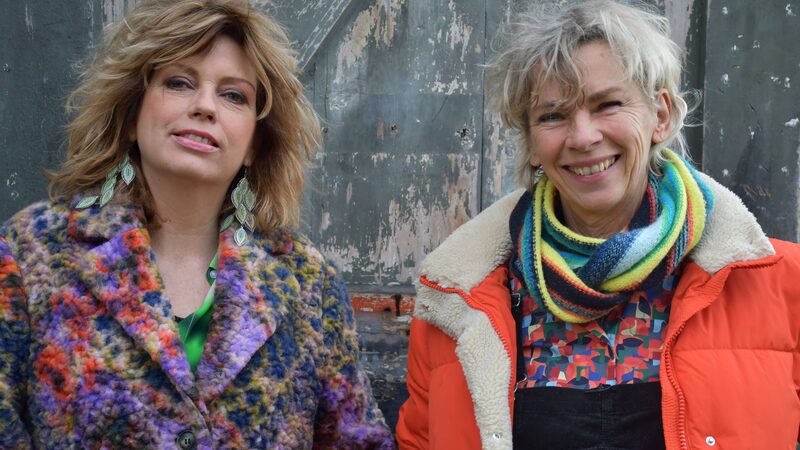 Twee vrouwen staan lachend naar de camera