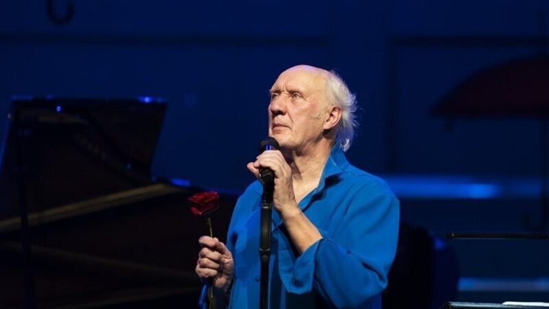 Zanger Herman van Veen in een blauw overhemd op het podium