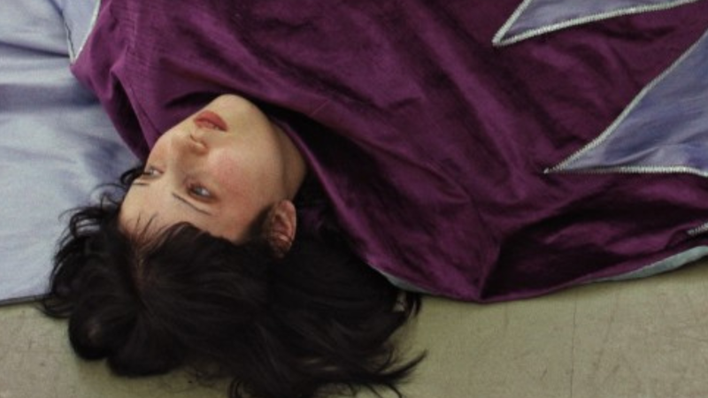 Vrouw ligt op de grond in paars gewaad