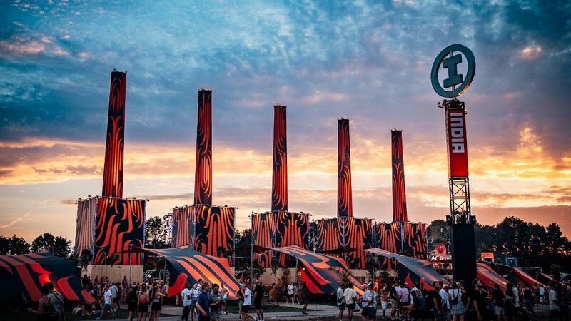 Een foto van een avondlucht op festival lowland met tegen de wolken aan de iconische oranje torens van het festival.