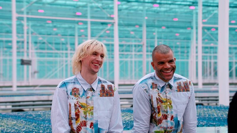 twee mannen staan in een kleurijk overhemd staan in een felbelichte kas met groene plantjes