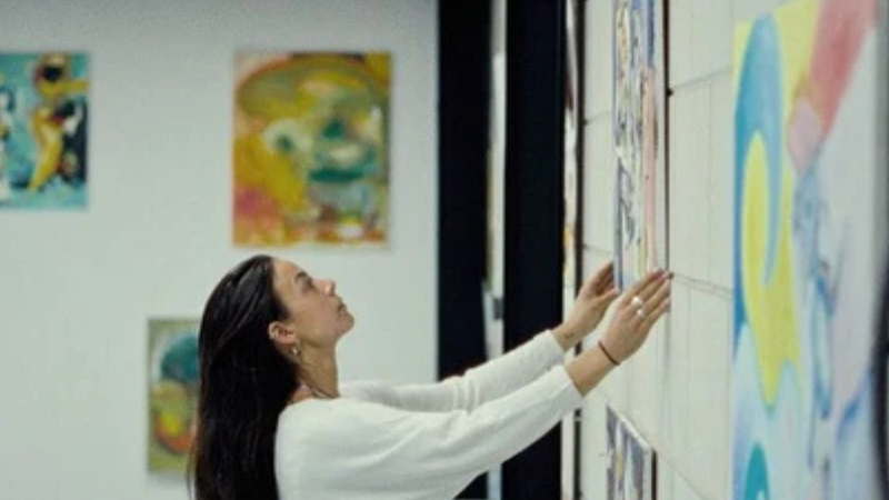 Vrouw hangt schilderij op in loods