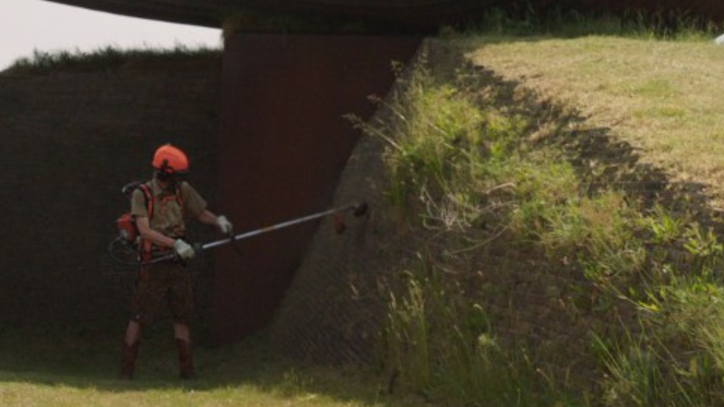 Een groot kunstwerk en een man met een grasmaaier