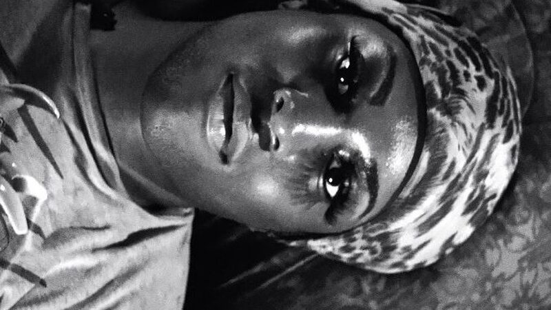 Een van de hoofdpersonen ligt op bed en kijkt verdrietig voor zich uit.