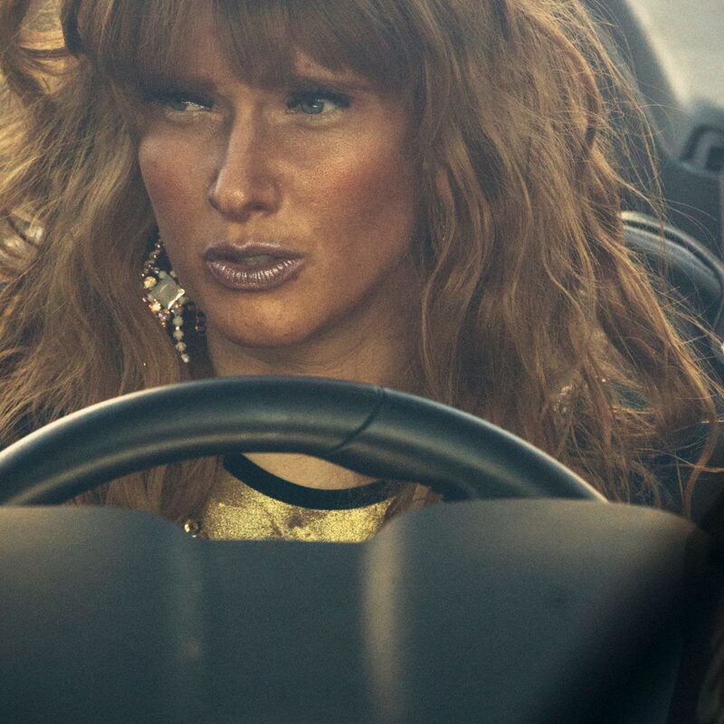 Een prachtige vrouw met gouden make-up zit achter het stuur