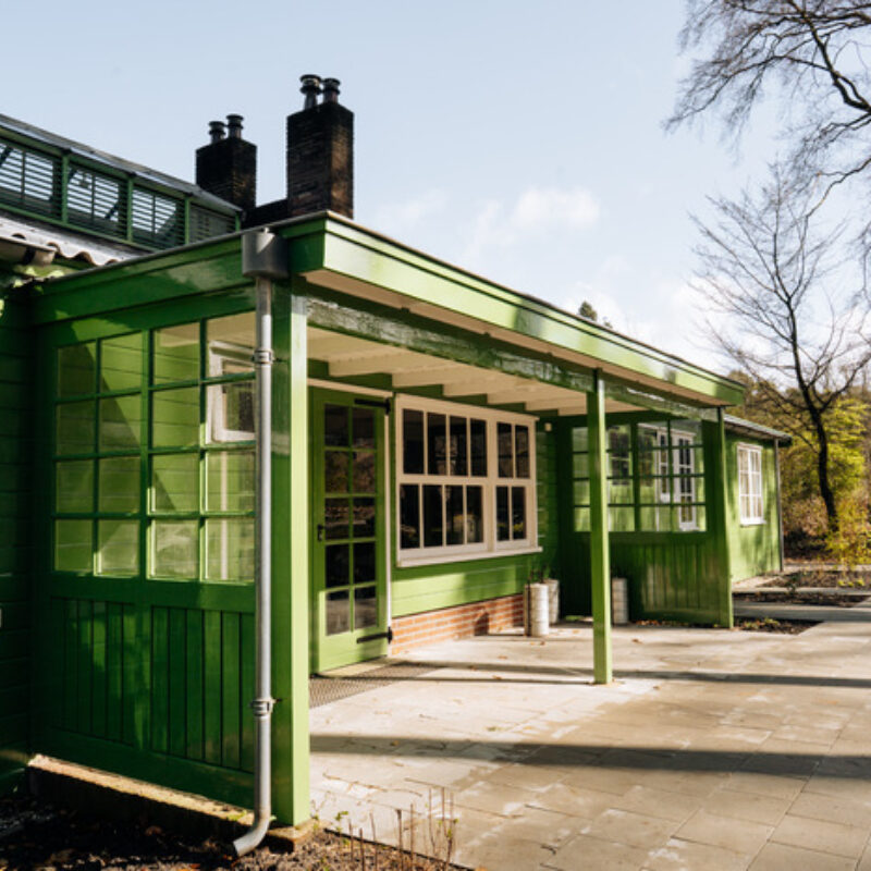 Barak gemaakt van lichtgroen gekleurd hout. De zon valt op het gebouw.
