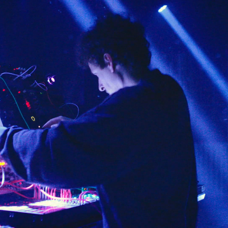 Een dj aan het werk op een blauw-verlicht podium