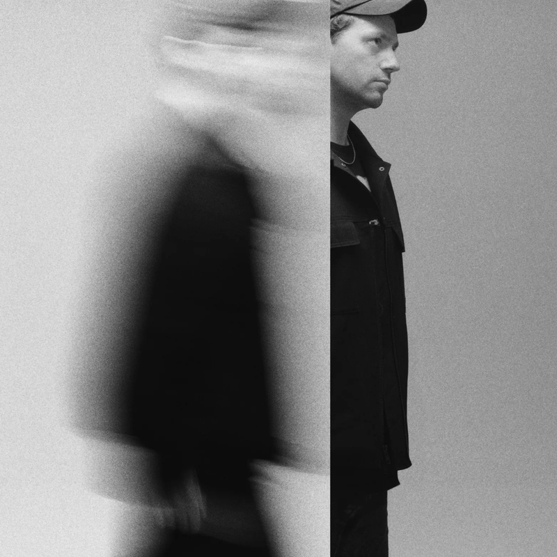 Een foto van Young Marco. Een man met een petje en hij kijkt naar de zijkant. Je ziet hem ten voeten uit.