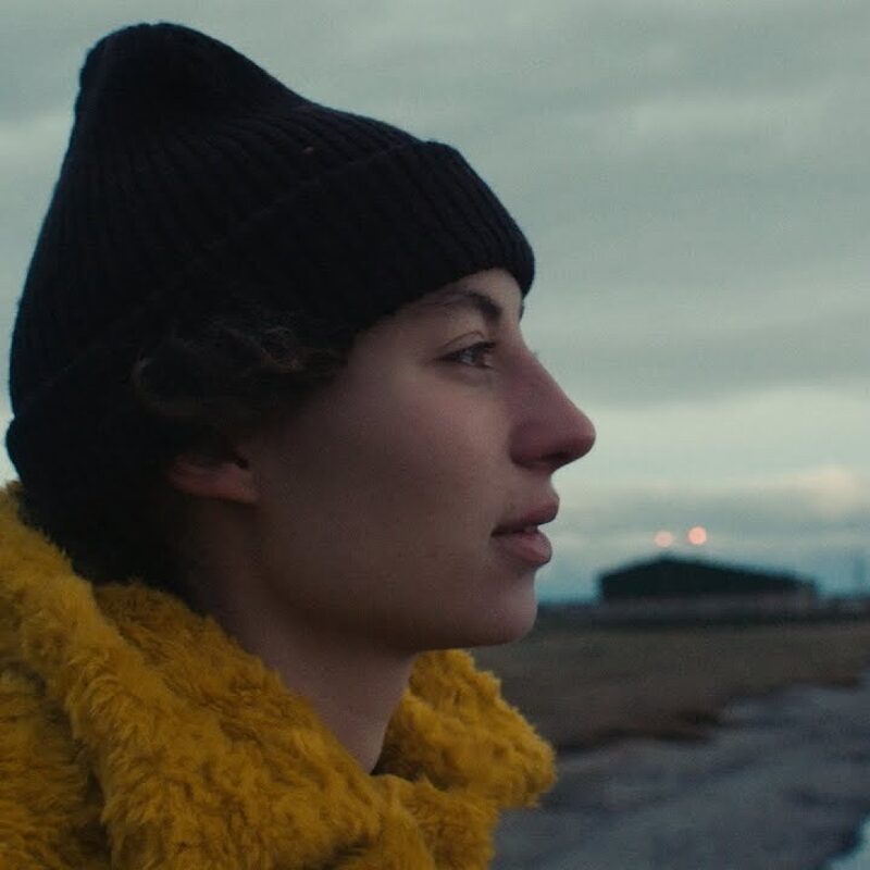 zijportret van Sarah Neutkens. Achter haar is een weg en een bewolkte lucht.