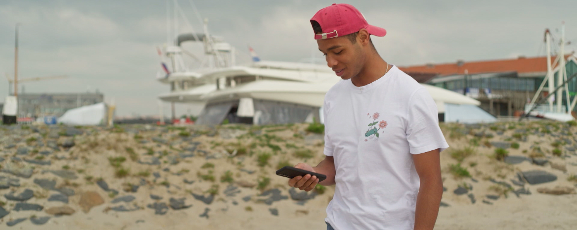 Jonge jongen met mobiel op het strand