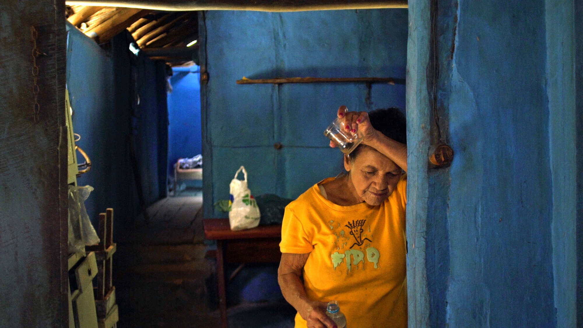 Hoofdpersoon van de documentaire, Alva, steunt tegen haar deur na het drinken van een glas water.