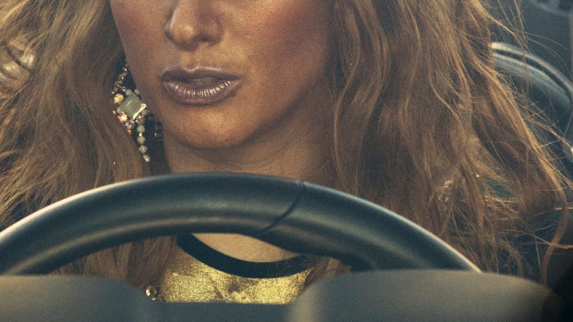 Een prachtige vrouw met gouden make-up zit achter het stuur