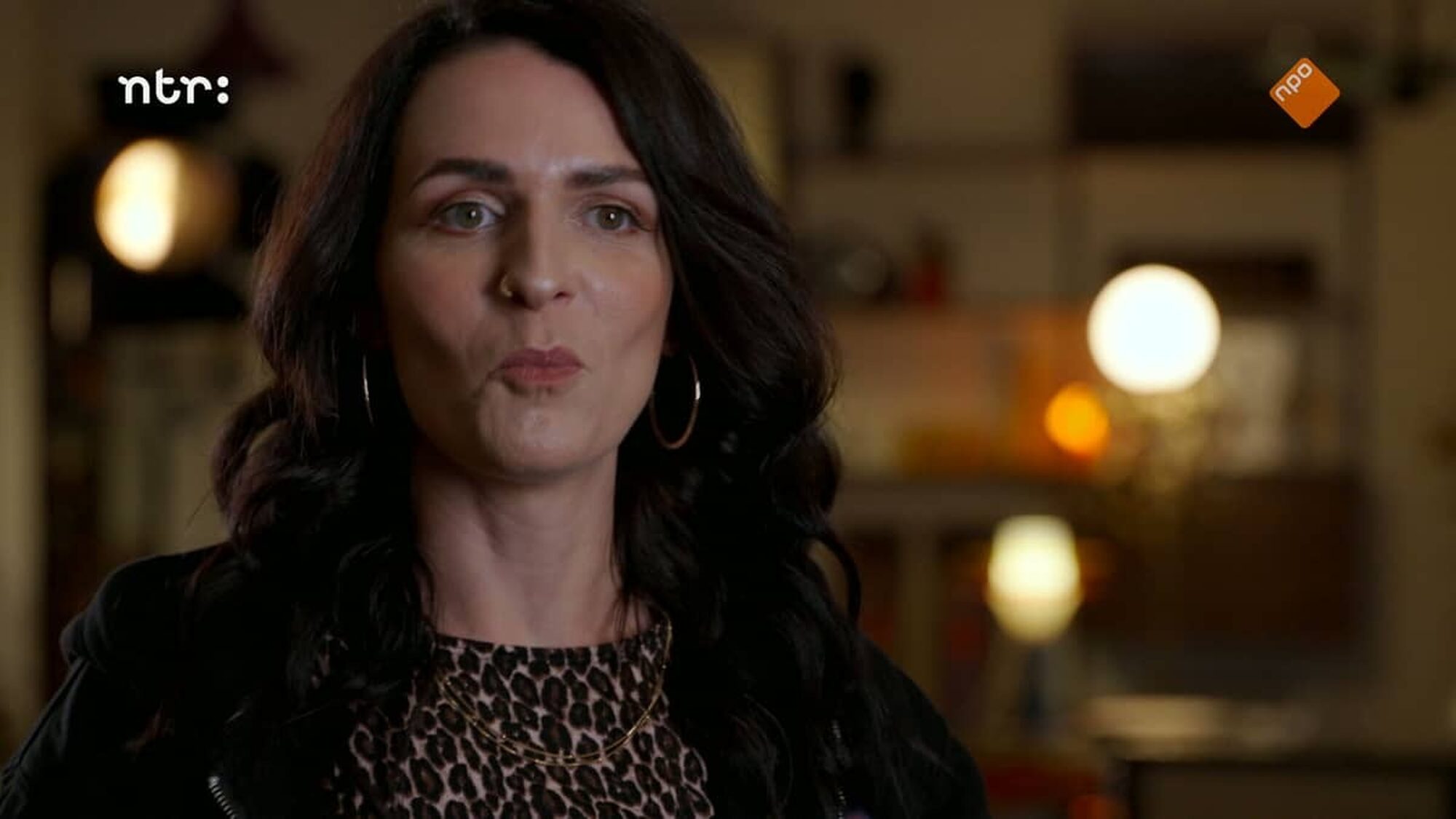 Vrouw met donkeren haren en pantertopje kijkt met getuite lippen naar de camera