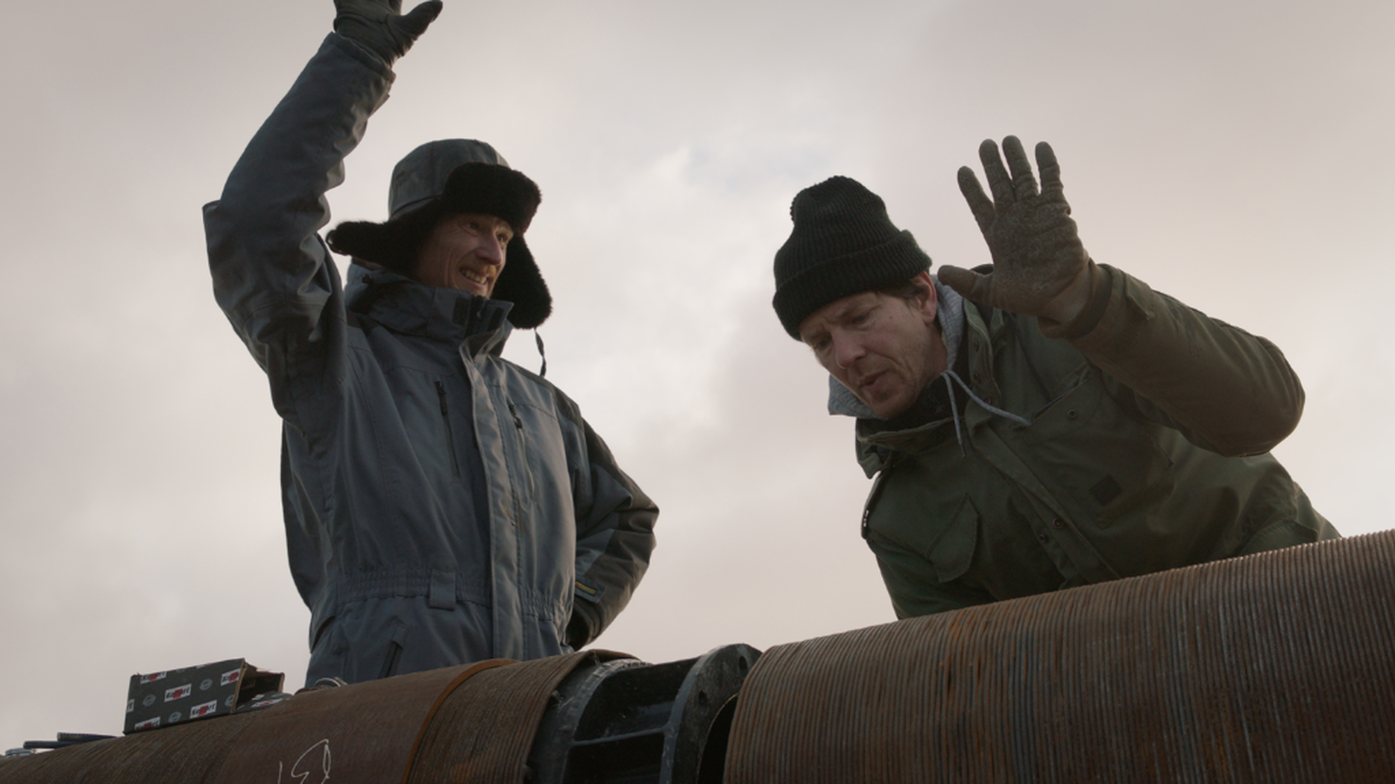 Twee broers die hun handen omhoog houden bij een buis