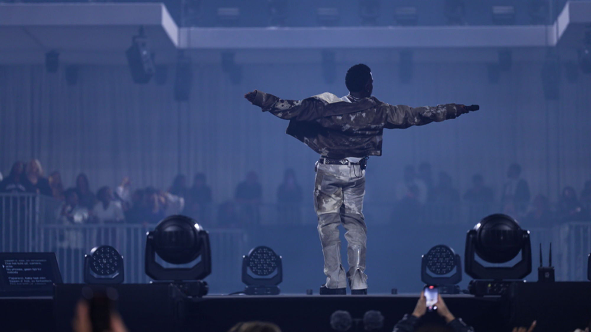 Frenna staat op het podium en steekt de microfoon naar het publiek