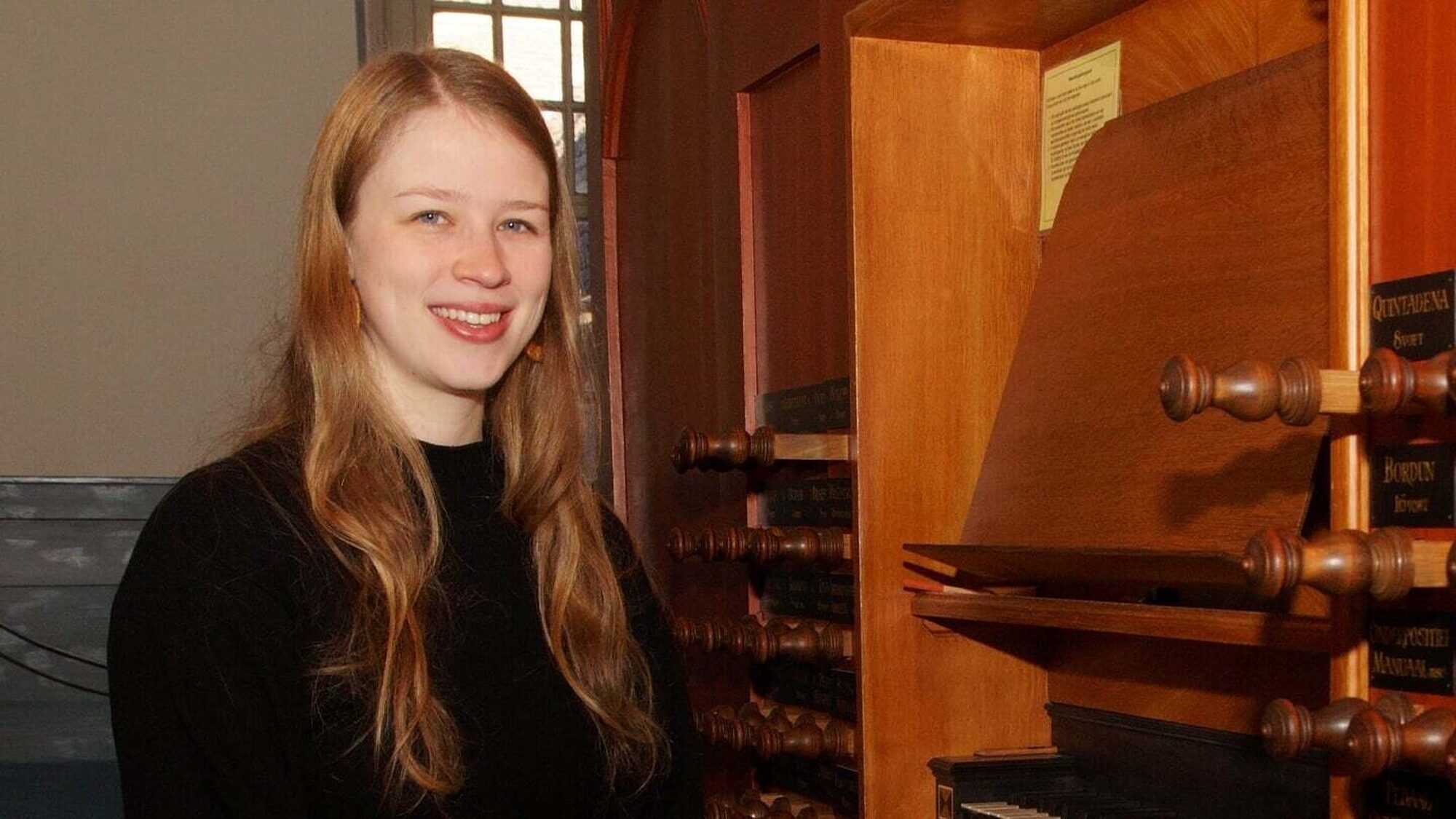 Vrouw zit lachend naast een orgel