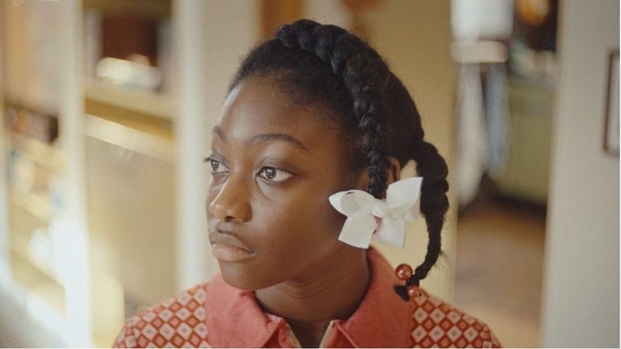 Meisje met witte bloem in haar vlecht kijkt naar iets dat buiten de camera is