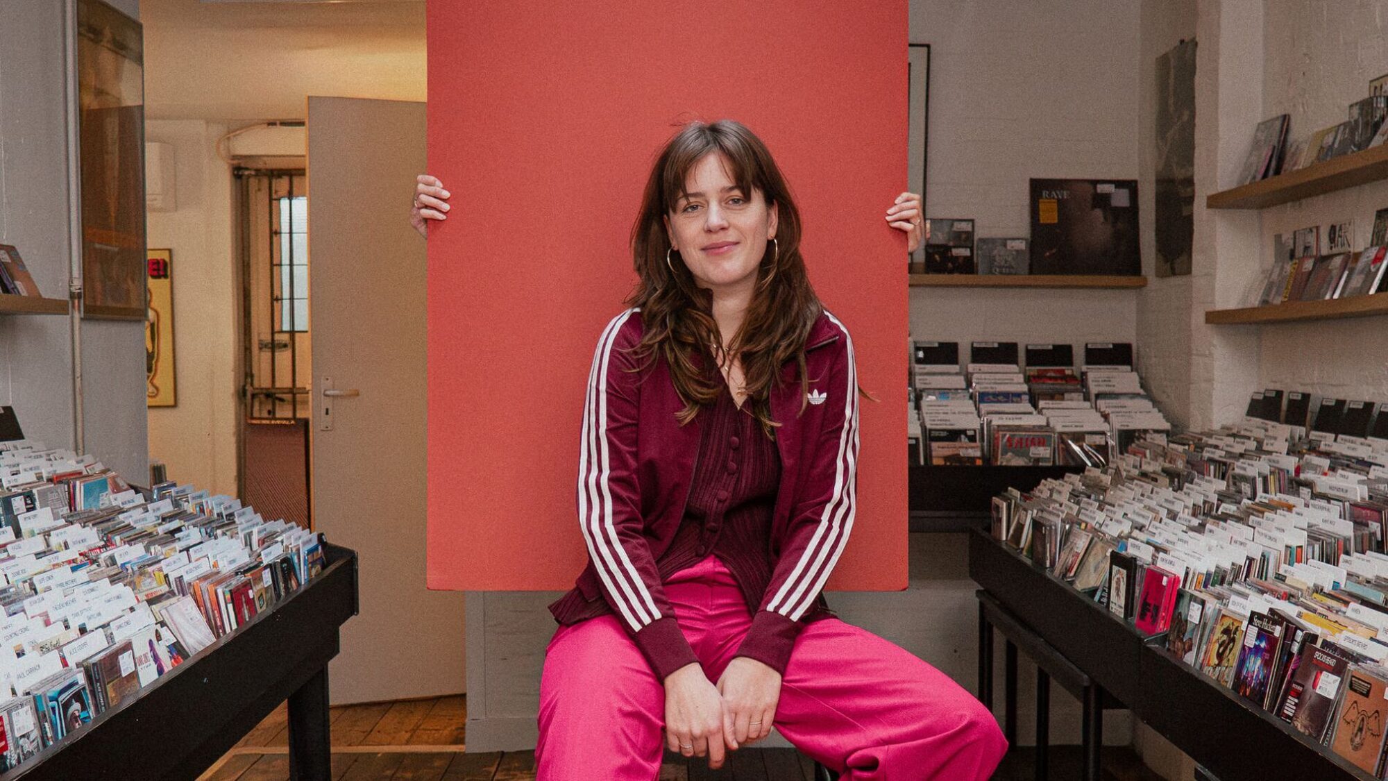 Host Adrienne Tilanus van podcast 50 jaar north sea jazz in kleurrijke kleding in een platenzaak