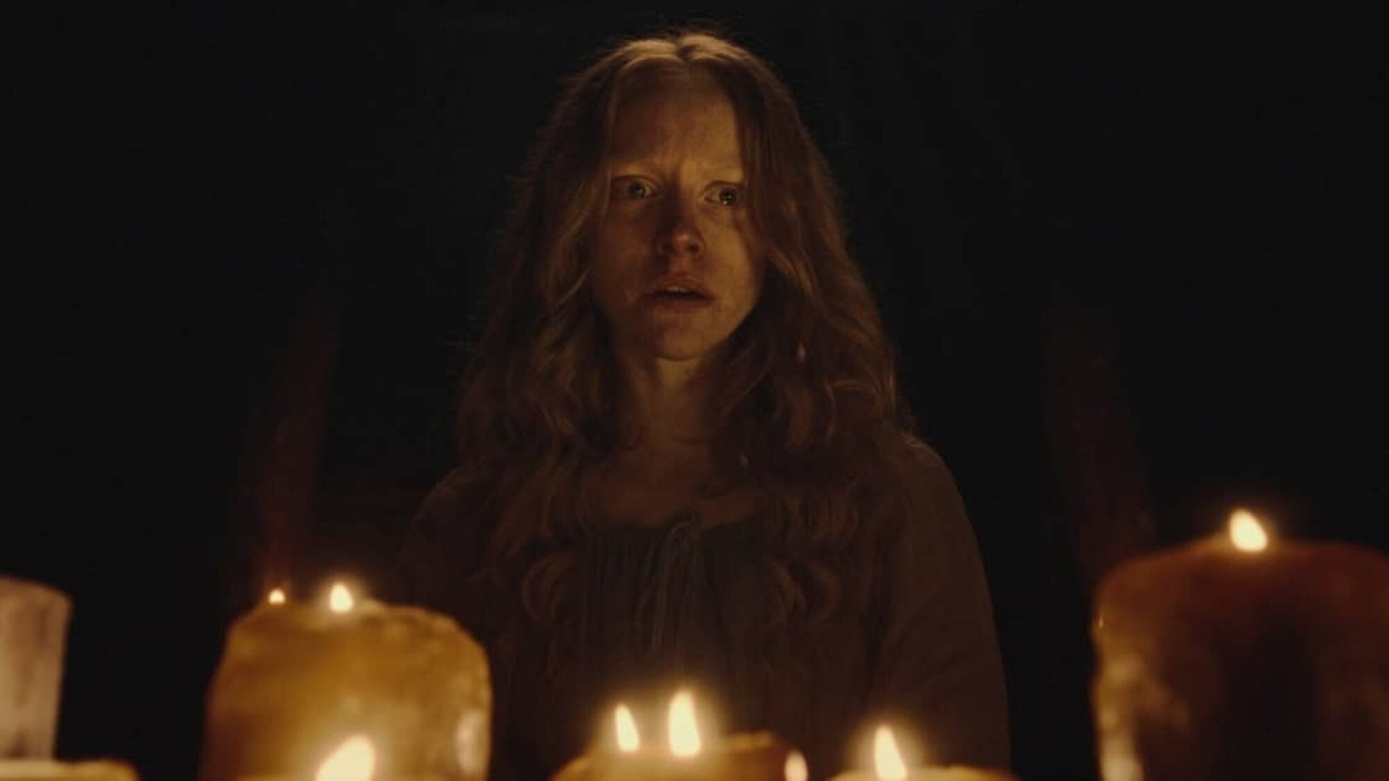 Vrouw kijkt angstig boven kaarsen