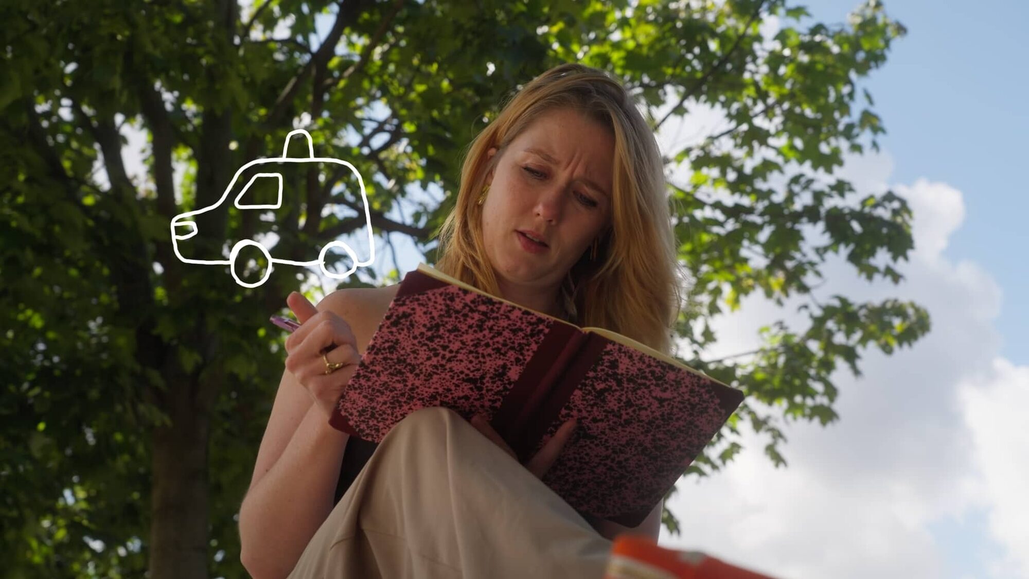 Jip van den Toorn tekent in een schetsboek terwijl ze tegen een boom leunt