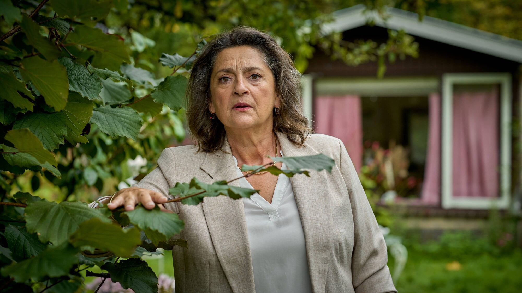 Hoofdpersonage uit Rust en Vreugd kijkt stiekem langs een heg