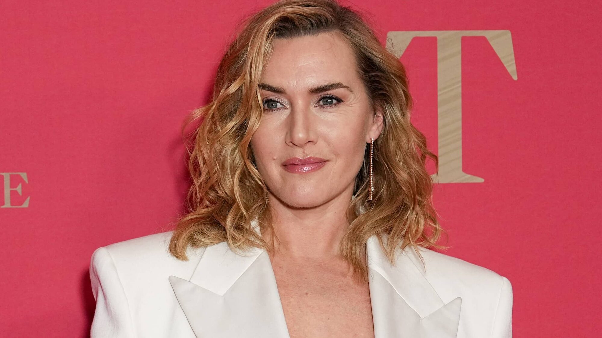 Actrice Kate Winslet staat voor een roze muur geposeerd