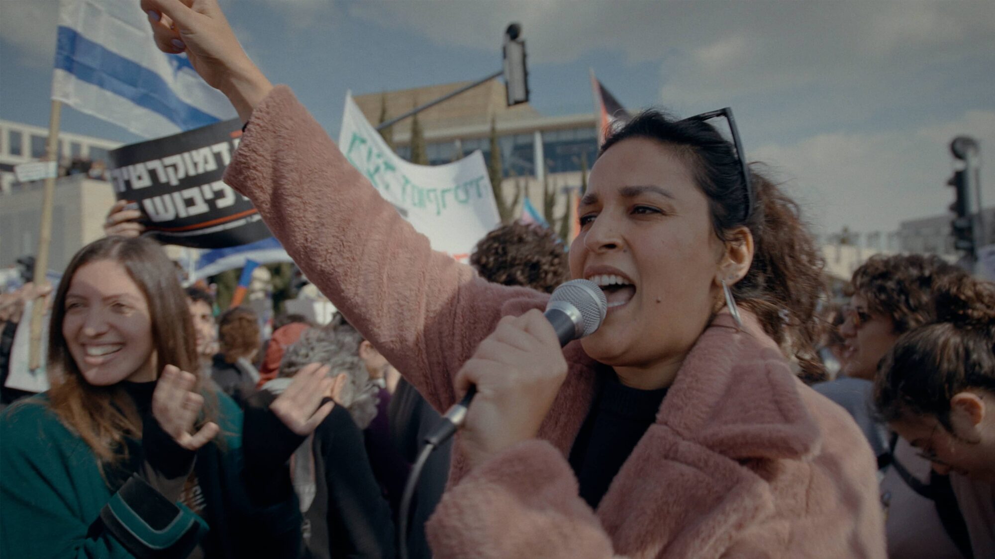 Noam Shuster-Eliassi staat in een demonstratie en roept in een microfoon