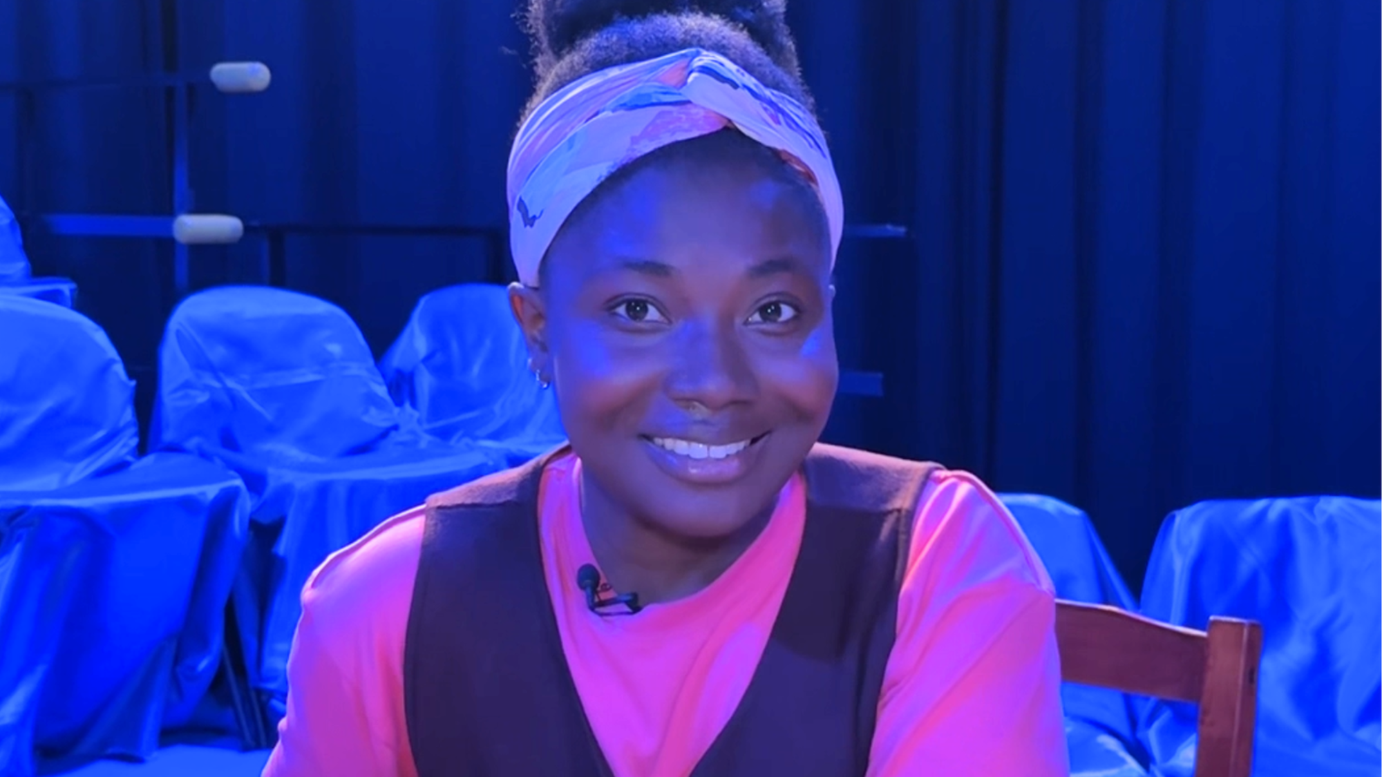 Op deze foto zien we Kimberley. Ze zit aan een tafel en kijkt vriendelijk lachend de camera in.