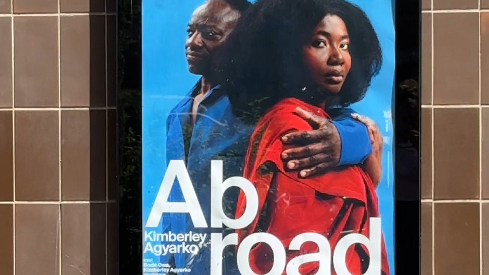 Op deze foto zien we de poster voor ABROAD op de muur van het theater hangen.