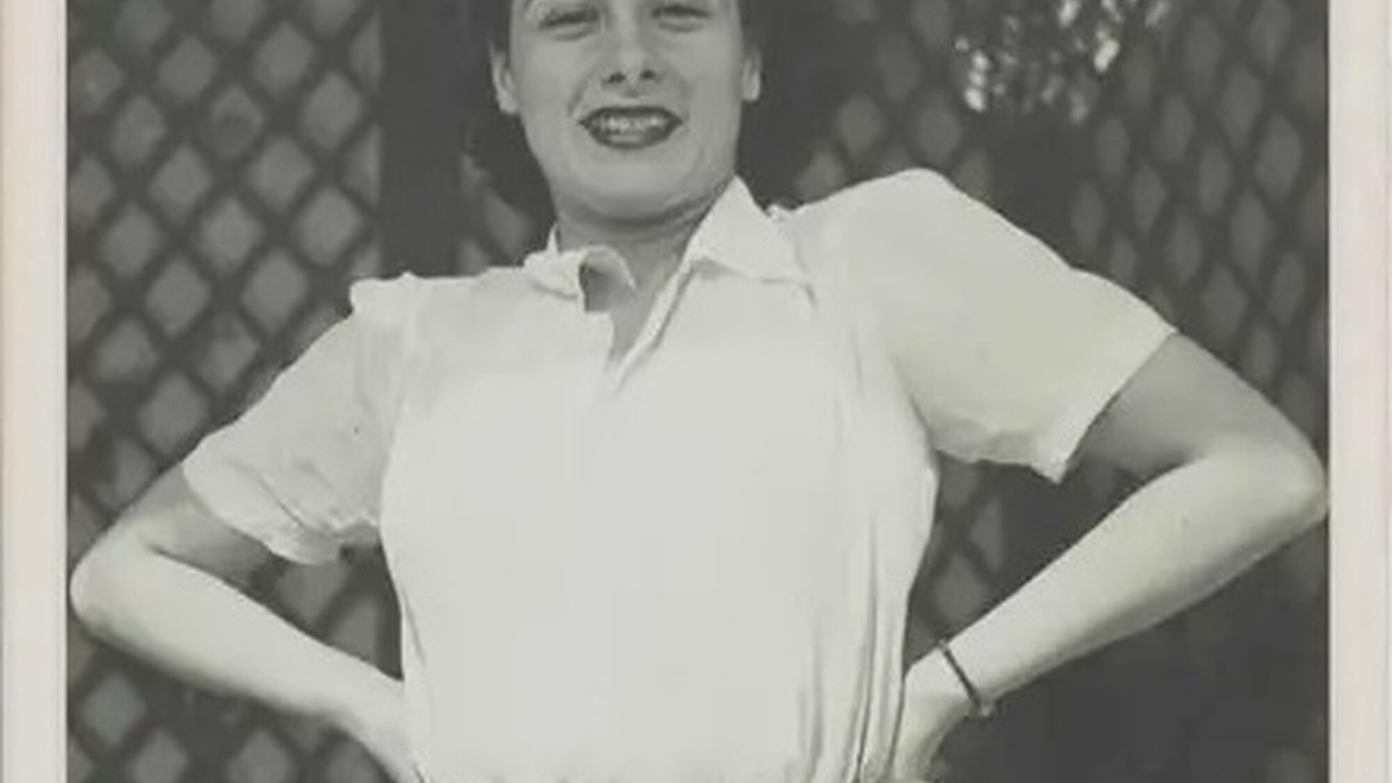 Gaby op een oude foto. Ze kijkt vrolijk in de camera en heeft haar handen in haar zij.