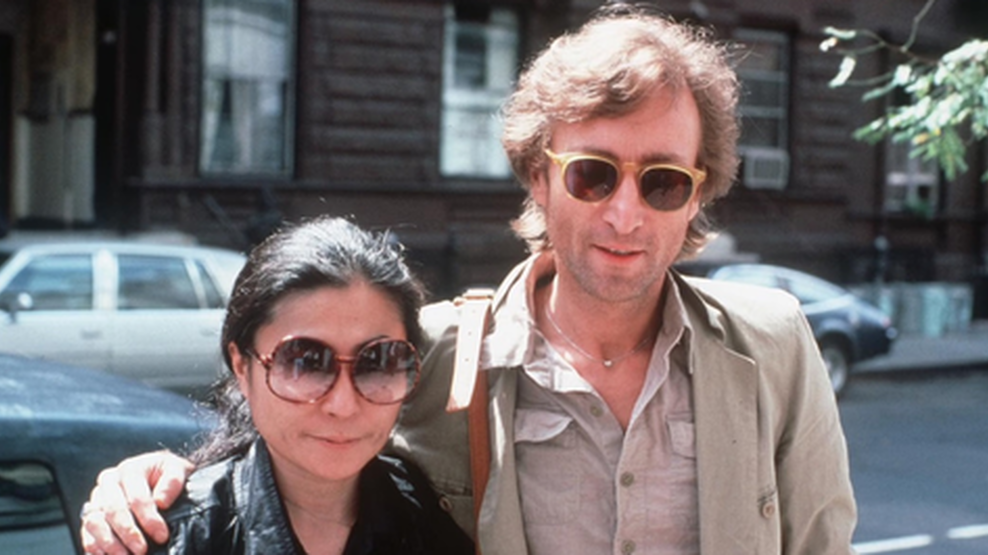 John Lennen samen met een vrouw met een zonnebril op straat