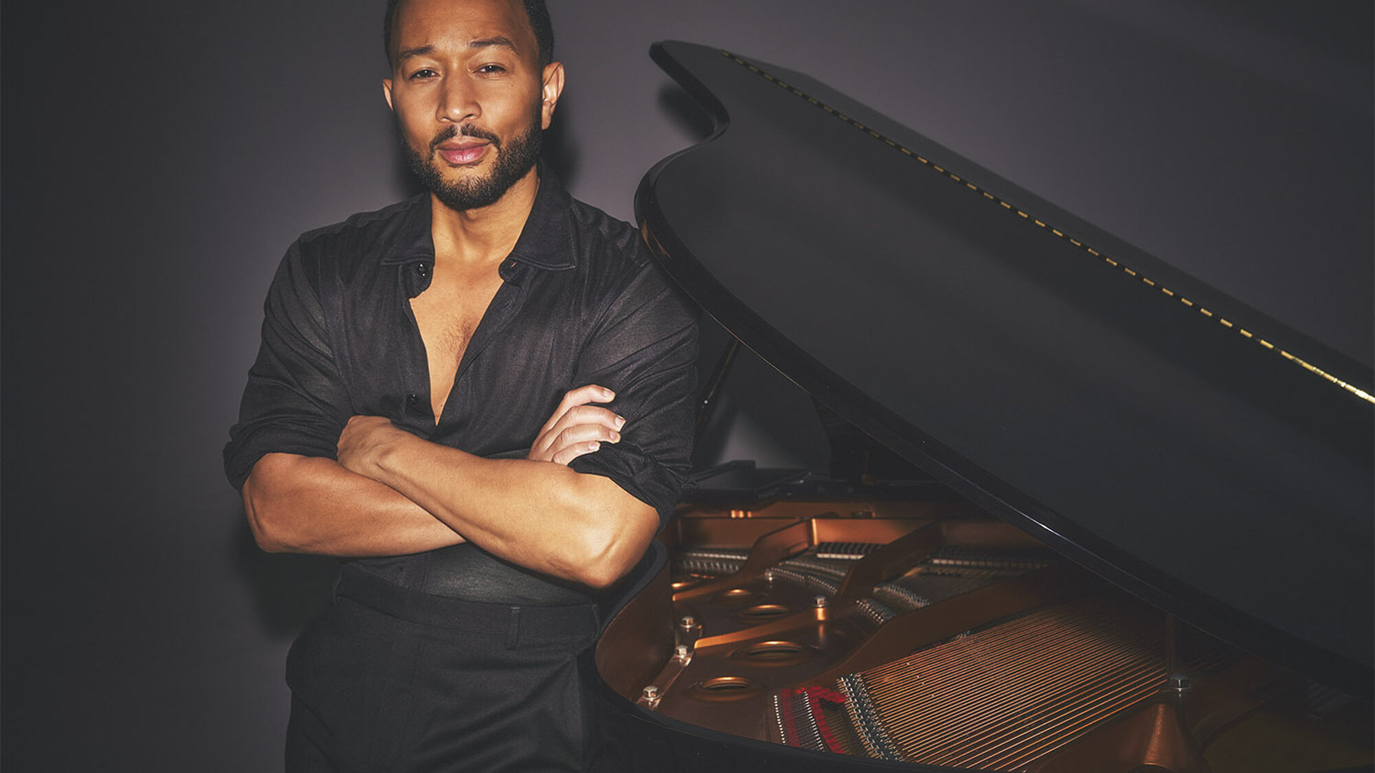 Zanger John Legend staat stoer geposeerd naast zijn vleugel