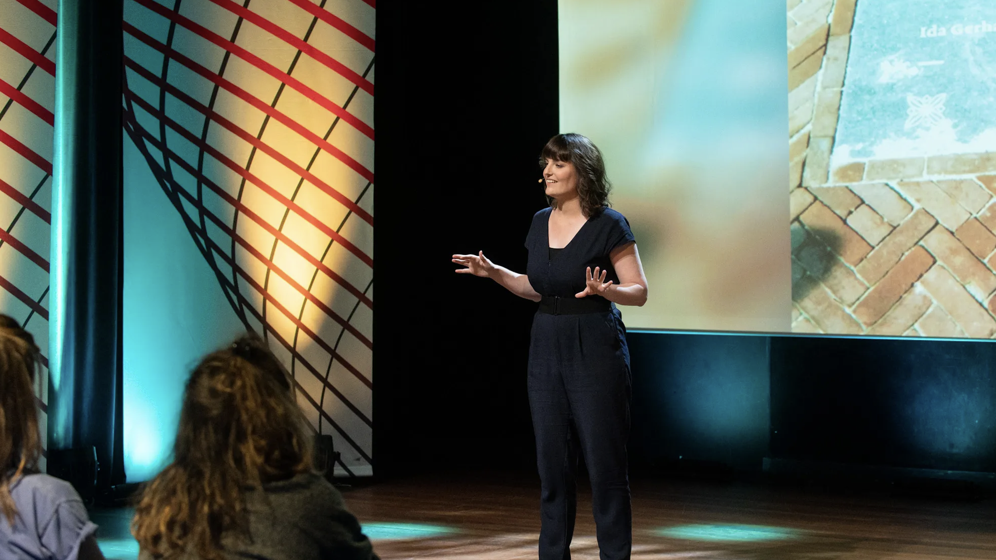Witte vrouw met zwarte haren staat te vertellen op een podium over poëzie